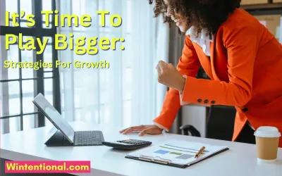 A woman in an orange jacket working at a laptop, titled It's Time To Play Bigger