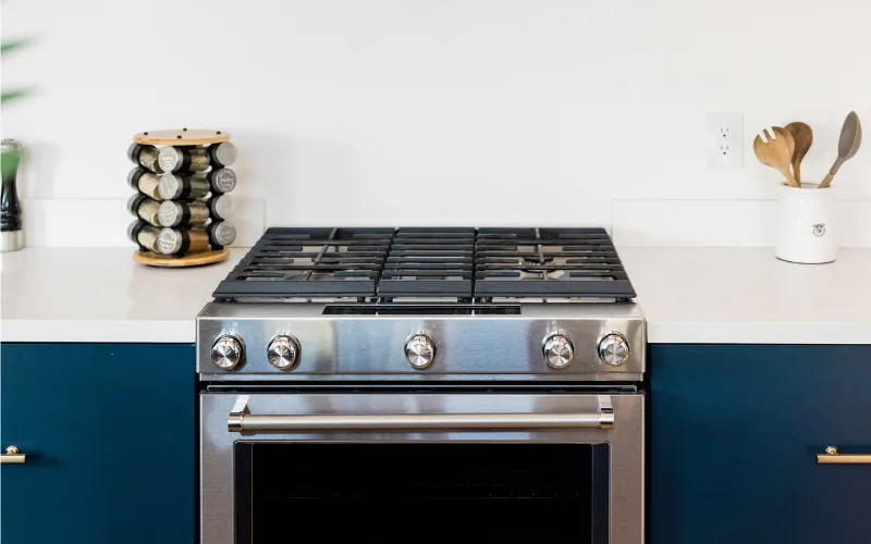 A clean white kitchen with a stove and spice rack
